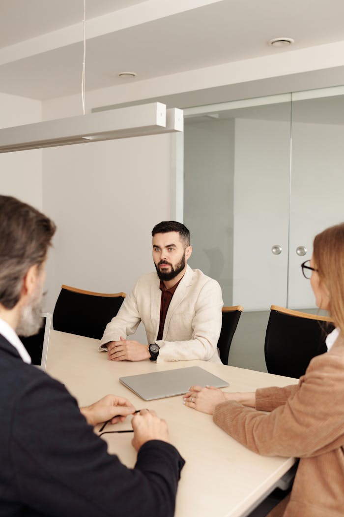 digital Three professionals engaged in a business meeting around a table in a modern office setting.