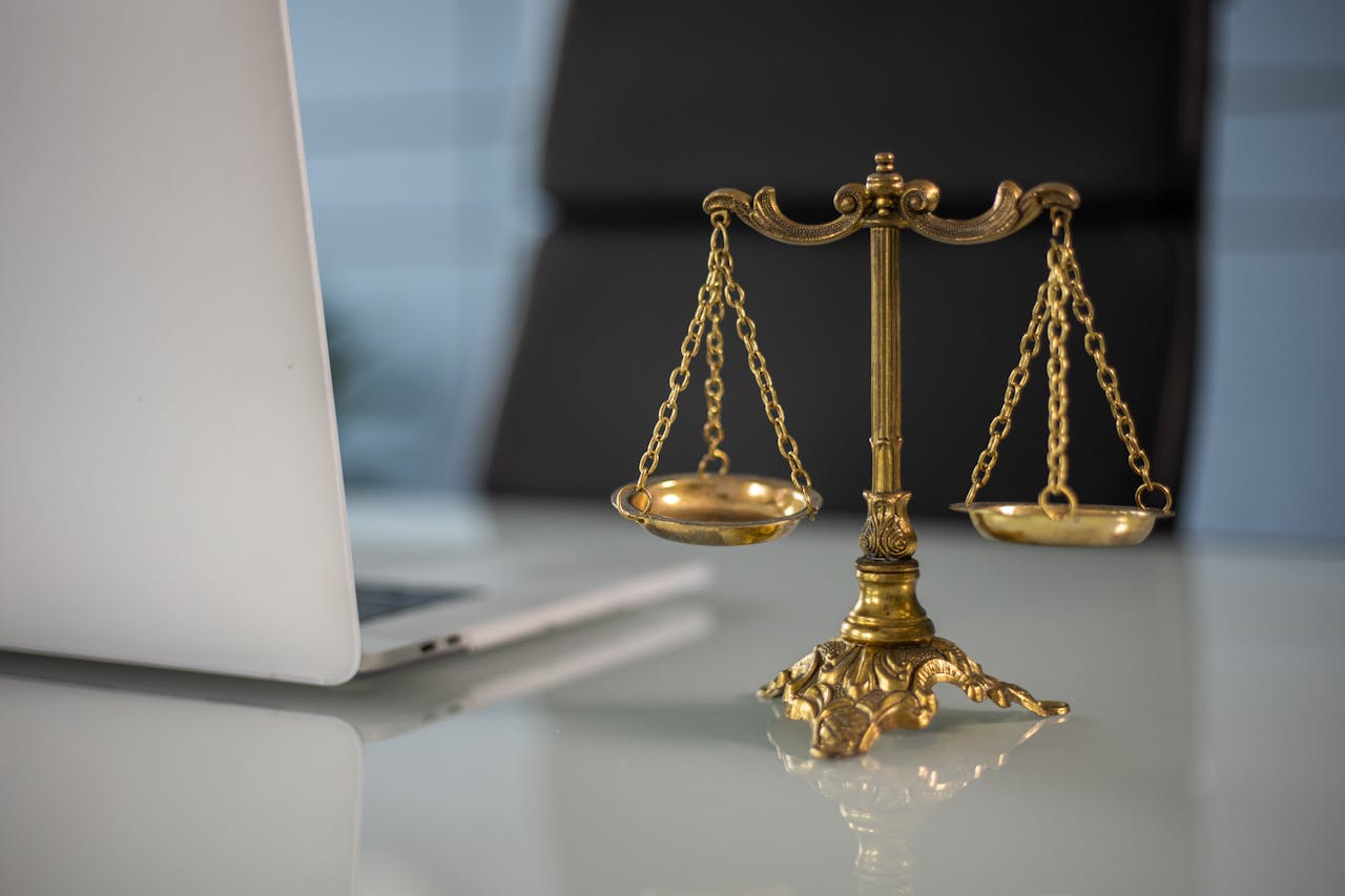 Services-03 Golden justice scales on a desk beside a laptop, symbolizing law and balance.